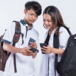 Dos estudiantes adolecentes observando un celular