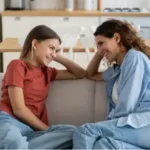 Madre hablando con su hija adolescente mientras ambas sonríen y fortalecen su comunicación.